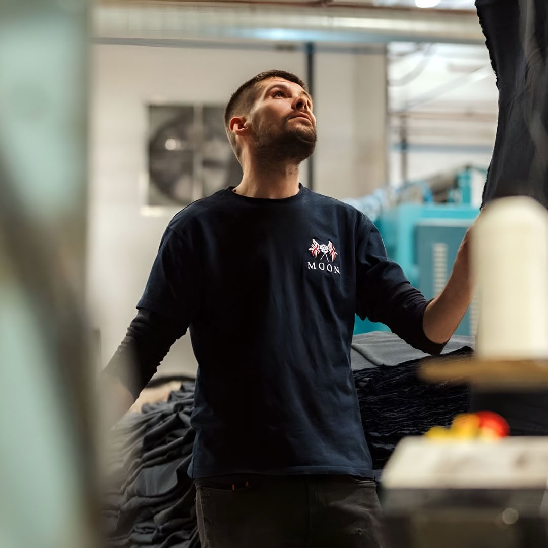 A member of the Moon team looks upwards within their factory, his jumper has the Moon logo embroidered to it