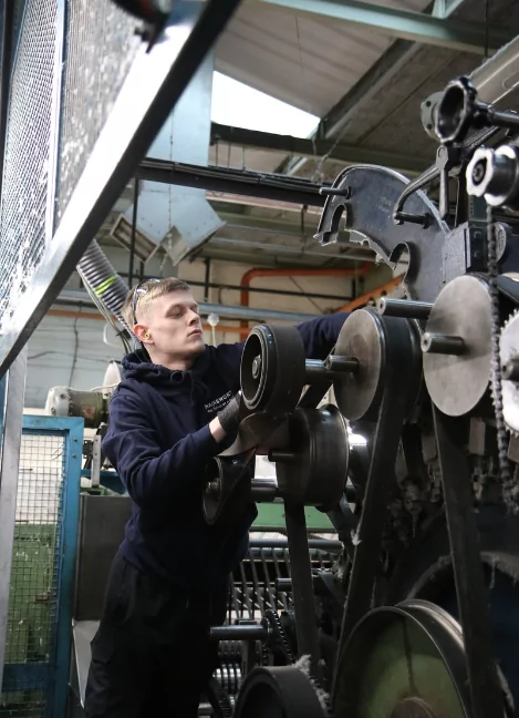 A young blonde haired man working on a piece of heavy machinery