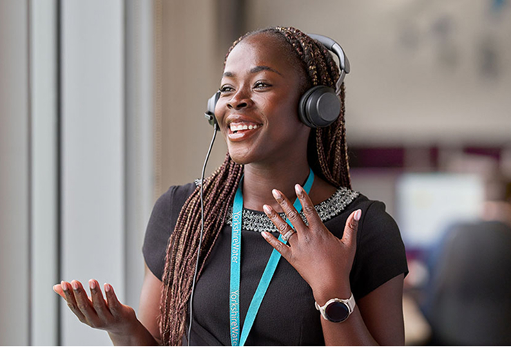 A black female Yorkshire Water staff member is speaking and on a headset to a customer and smiling
